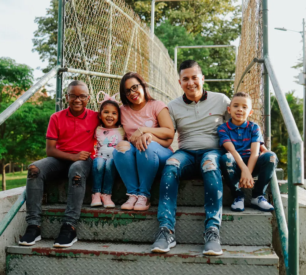 Familia de cinco integrantes sentada junta al aire libre